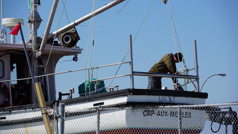 Un homme travaille sur un bateau à terre au port de Rimouski.