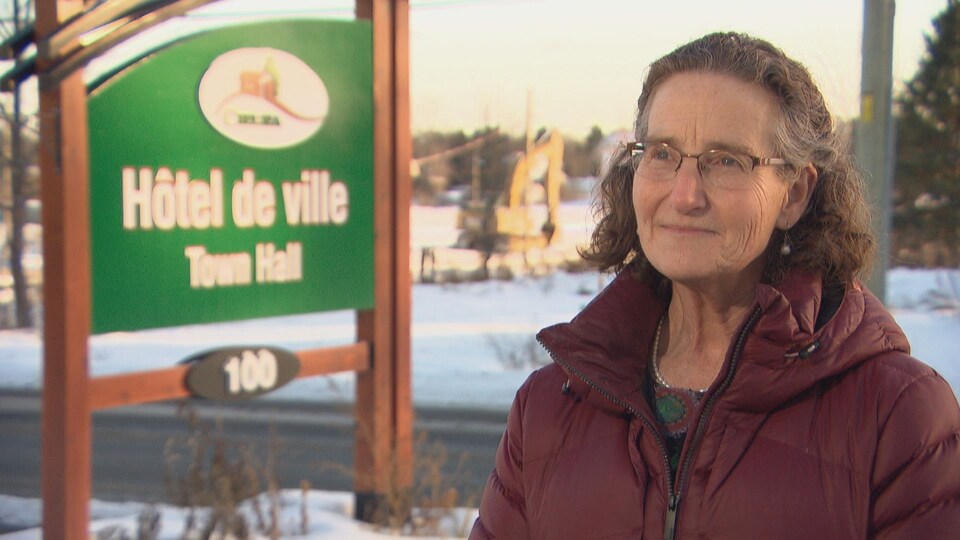 Caryl Green répond aux questions d'une journaliste devant l'enseigne de l'hôtel de ville de Chelsea.