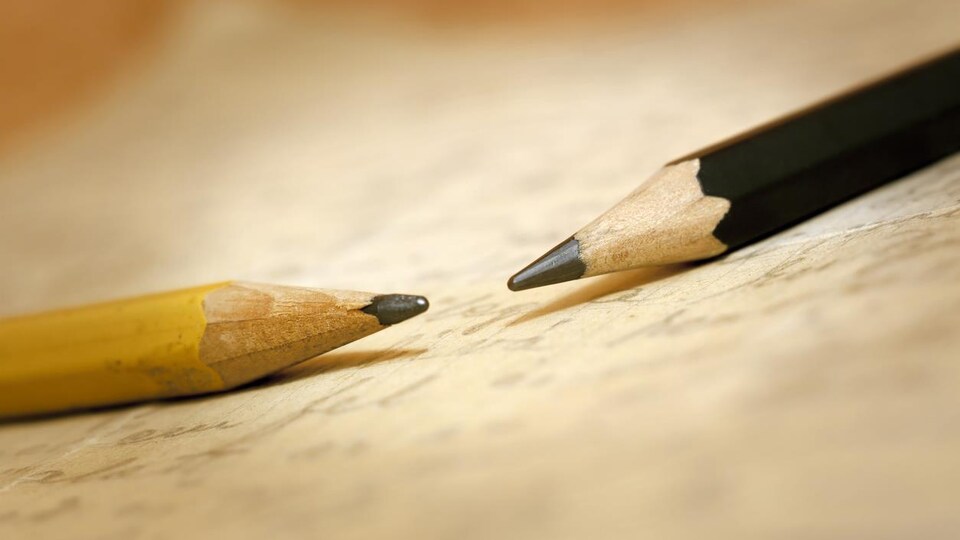 Deux crayons de bois sur un papier jauni.
