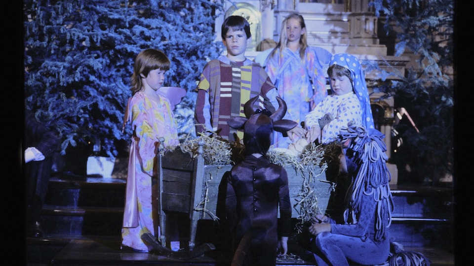 Enfants déguisés en Marie, Joseph, boeuf, âne et anges, qui entourent le petit Jésus.