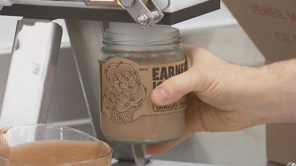 Un pot de crème glacée est rempli par une machine