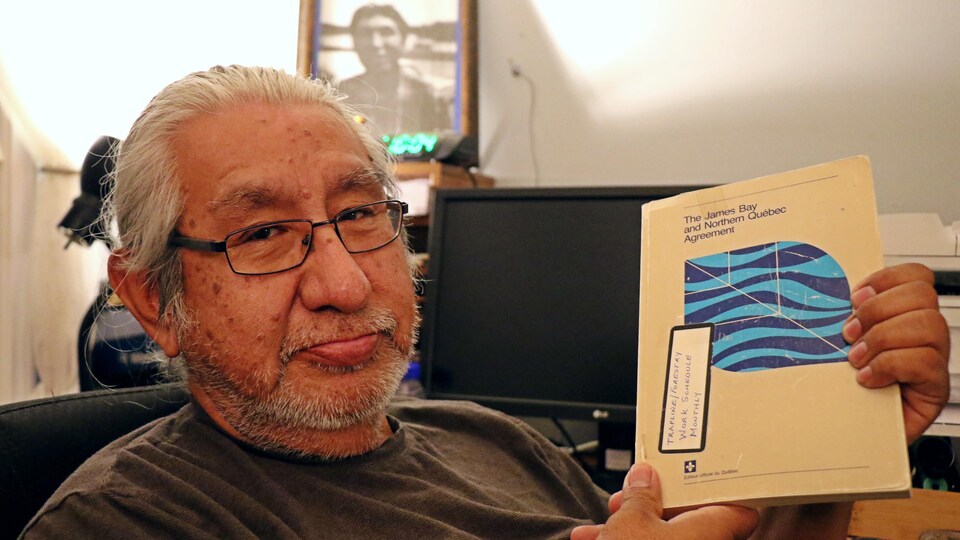 Un homme pose avec un livre à la main.