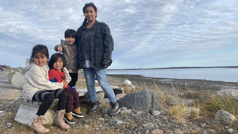 Une femme crie et trois de ses enfants posent devant un lac.