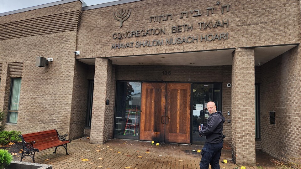 Un policier du SPVM, devant la porte d'entrée de la synagogue Congrégation Beth Tikvah, enquête sur l'attaque incendiaire qui est survenu dans la nuit de lundi à mardi.