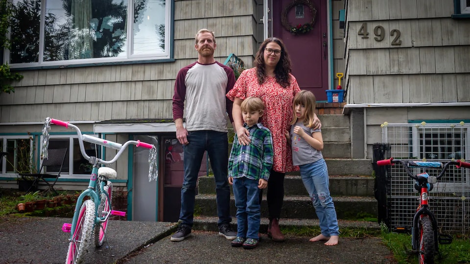 Un homme, une femme et deux enfants devant leur logement.