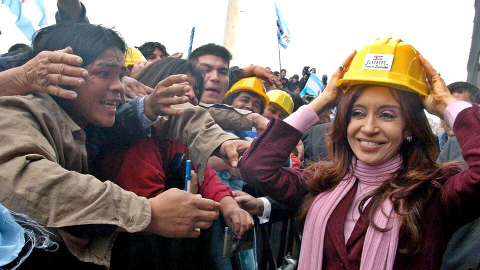Cristina Kirchner marche dans une foule en portant un casque de construction.