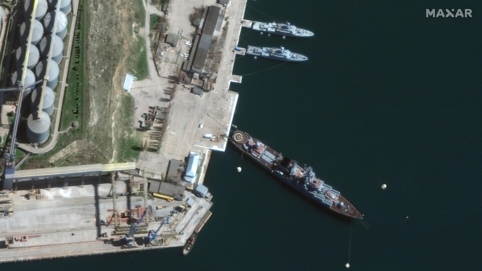 Une photo aérienne montre un croiseur amarré dans un port.