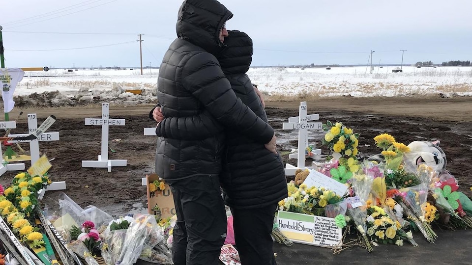 Deux personnes se serrent dans leurs bras devant les objects déposés sur le sol.
