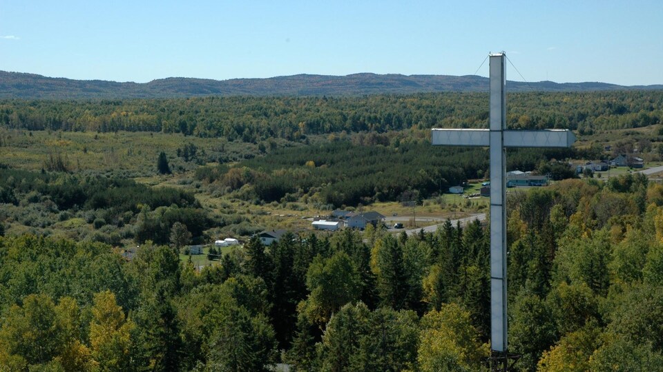 Une grosse croix surplombe un village.