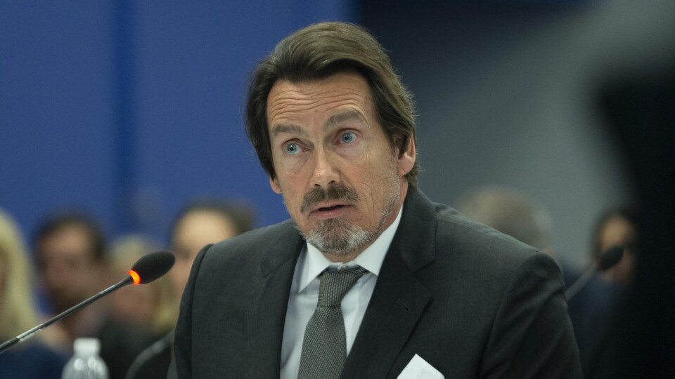 Pierre Karl Péladeau assis, devant un micro.