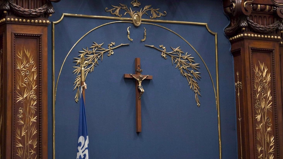 Une croix de bois sous des éléments décoratifs dorés.