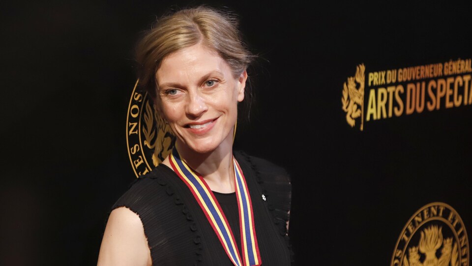 The woman wore a medal and smiled at the cameras on the red carpet of a gala. 