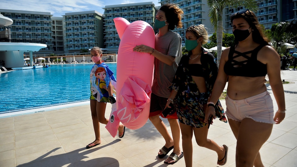 Quatre personnes se promènent près de la piscine d'un complexe hôtelier.