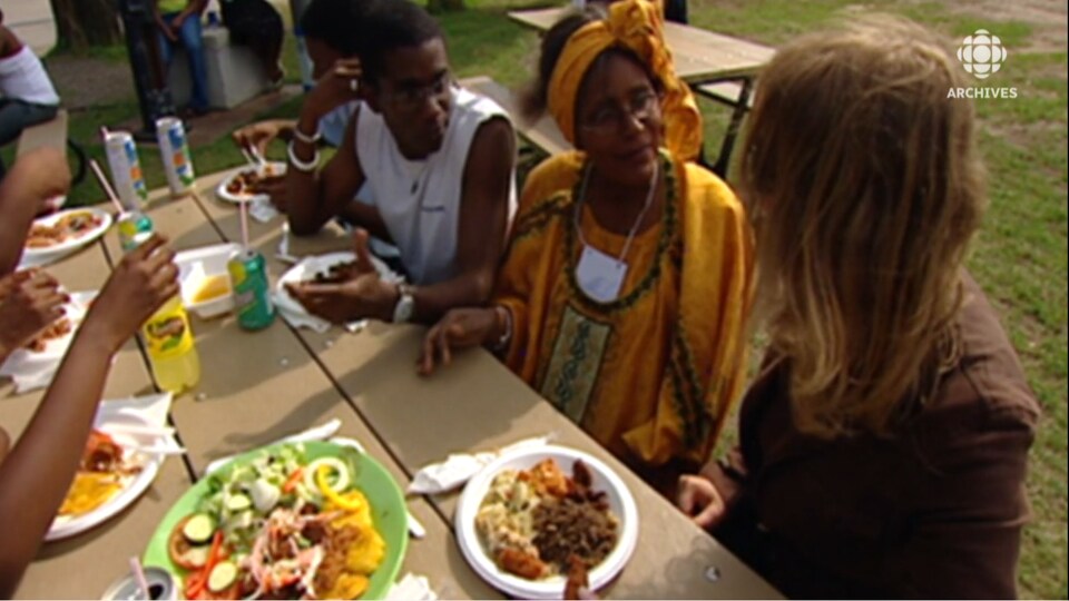 Une journaliste est assise à une table de pique-nique avec une famille haïtienne.