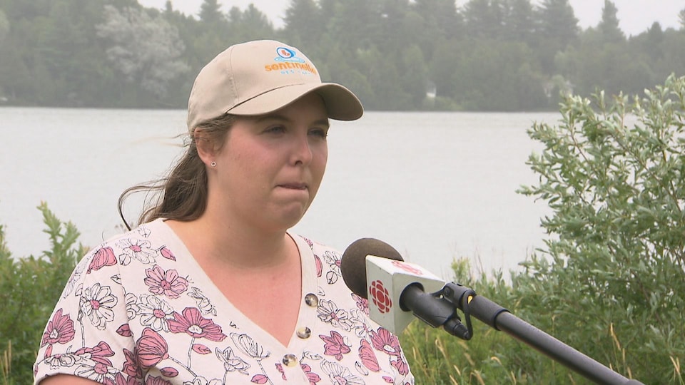 Anne Bolduc accorde une entrevue à une équipe de Radio-Canada devant un lac. 