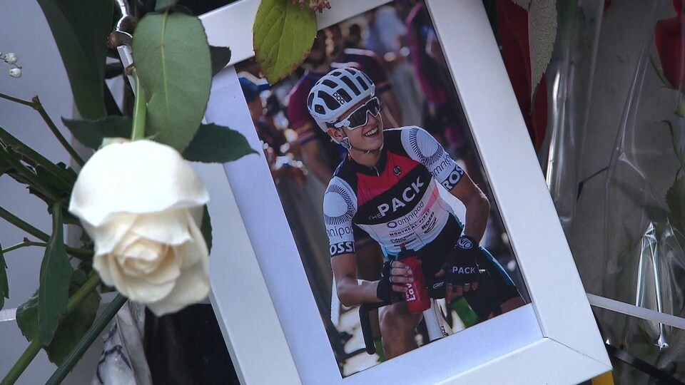 Photo du cycliste Clément Ouimet accrochée sur un poteau de la voie Camillien-Houde, sur le mont Royal, avec une rose blanche.