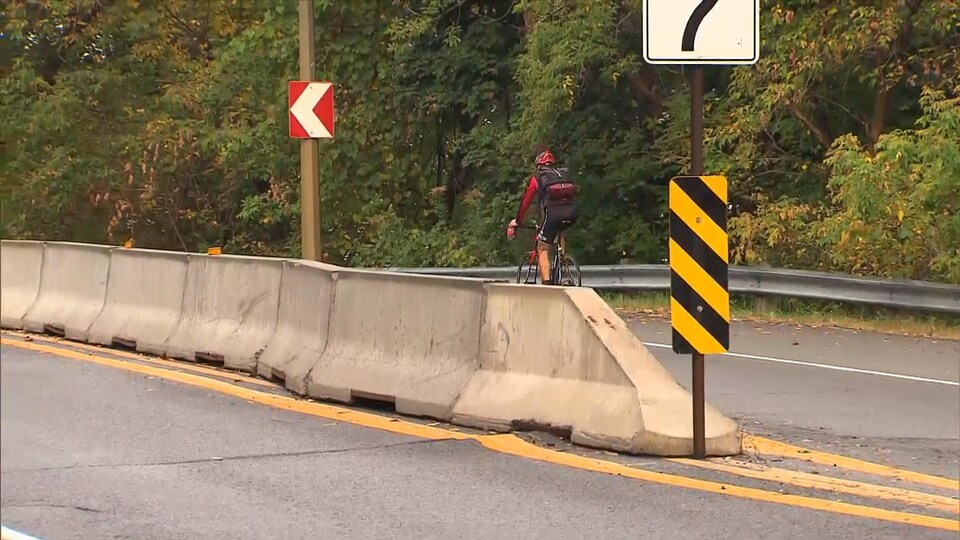 Un cycliste sur une portion de la voie Camillien-Houde séparée par des murets, sur le mont Royal