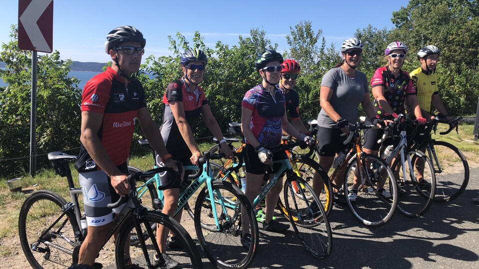 Plusieurs cyclistes posent, à l'extérieur, sur leur vélo.