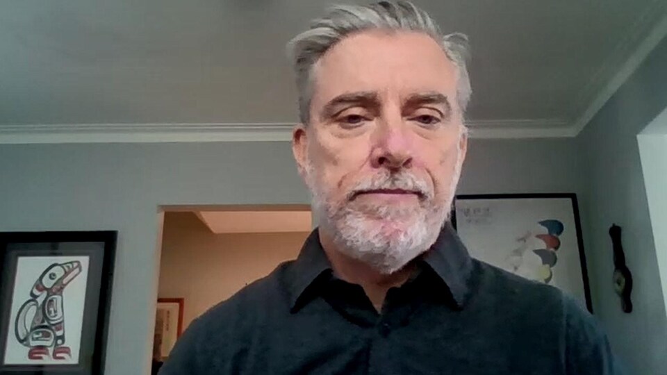 Un homme, dans son salon, en vidéoconférence.