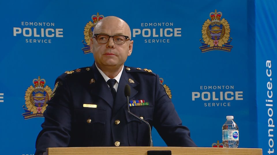 Dale McFee s'adresse à la presse devant un décor où on voit le logo du Service de police d'Edmonton.