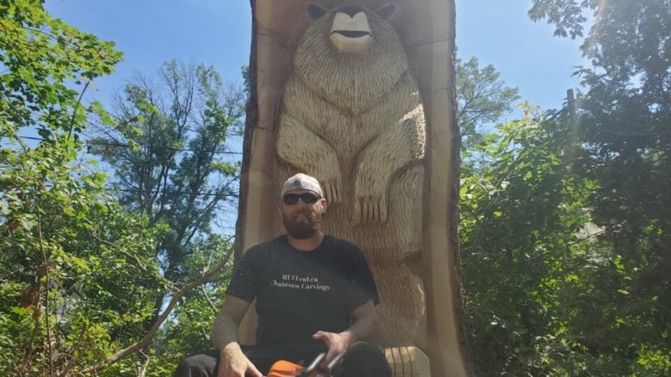 Dale Ruff, originaire de Dorval, pose devant la sculpture d'un ours.