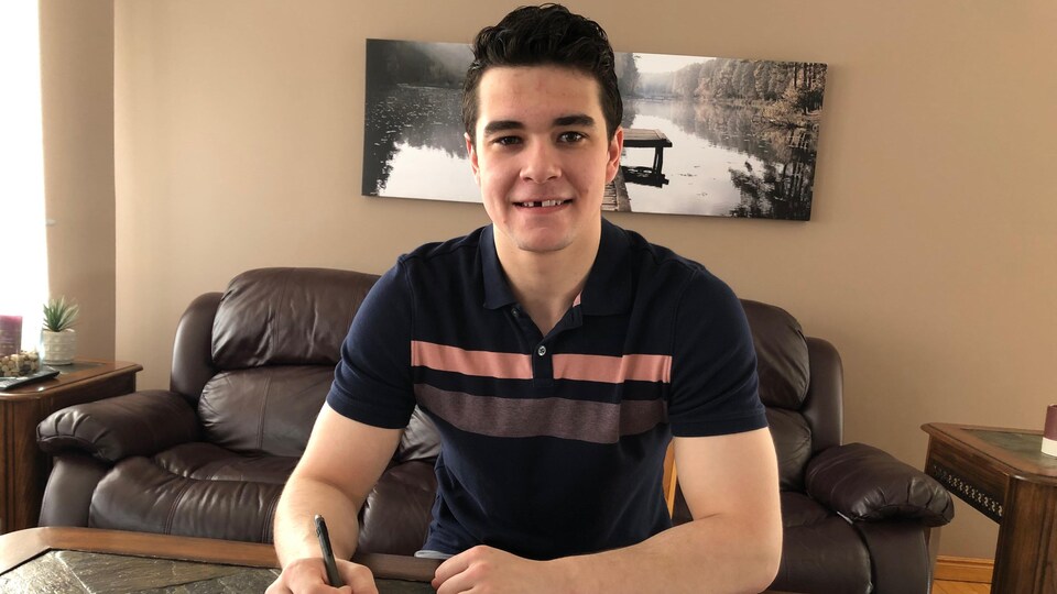 Damien Giroux signe son contrat sur sa table de cuisine.
