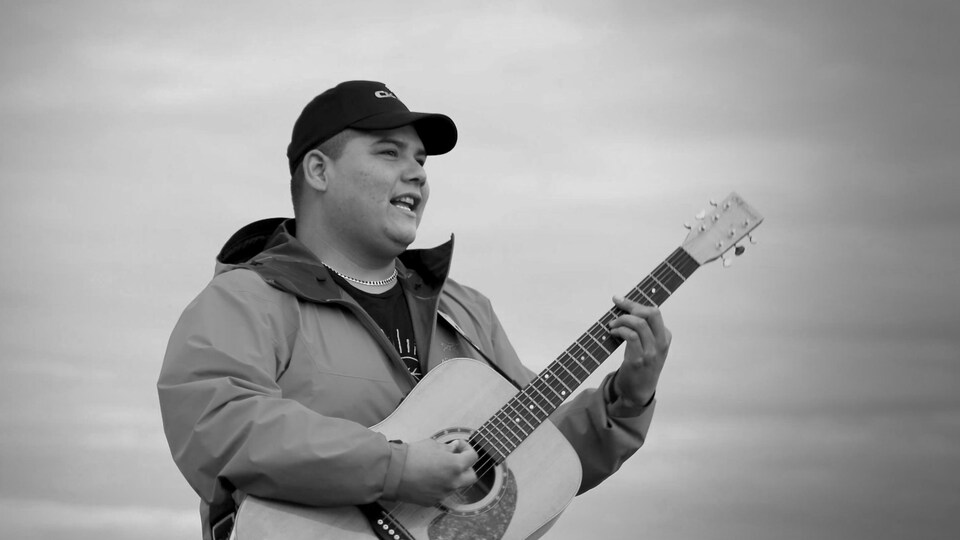 Dan-Georges avec sa guitare à l'extérieur.