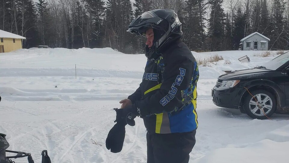 Dan LeMay porte une tenue hivernale et un casque et il enfile ses gants.