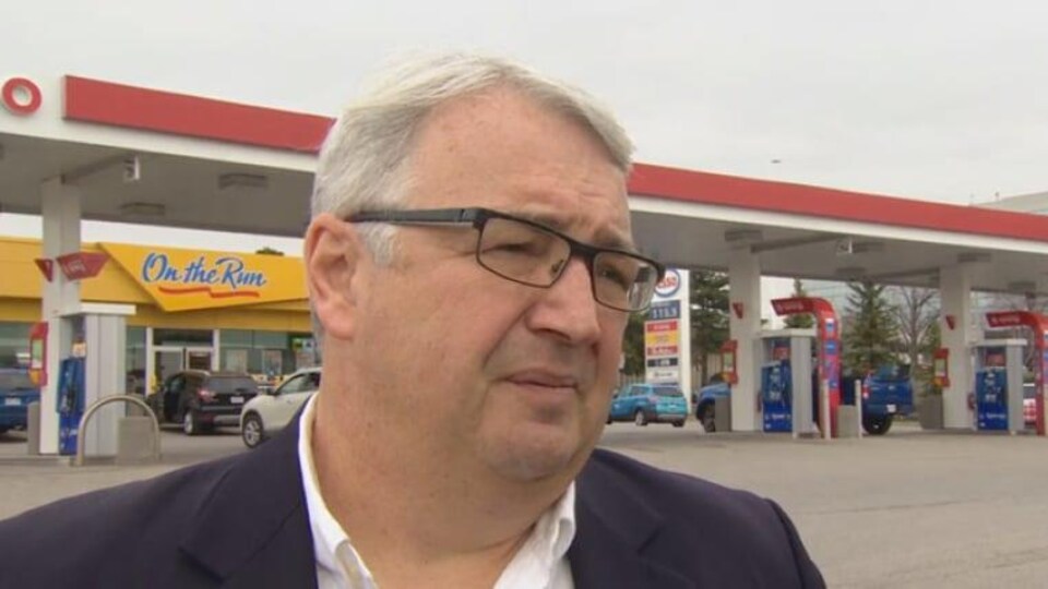 Gros plan sur Dan McTeague devant une station d'essence.