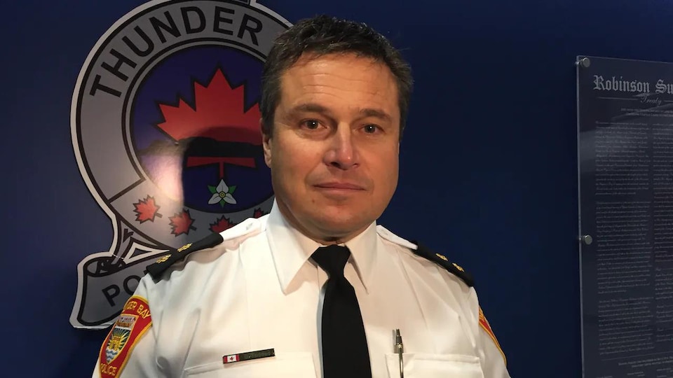 Portrait de Dan Taddeo devant le logo du Service de police de Thunder Bay.