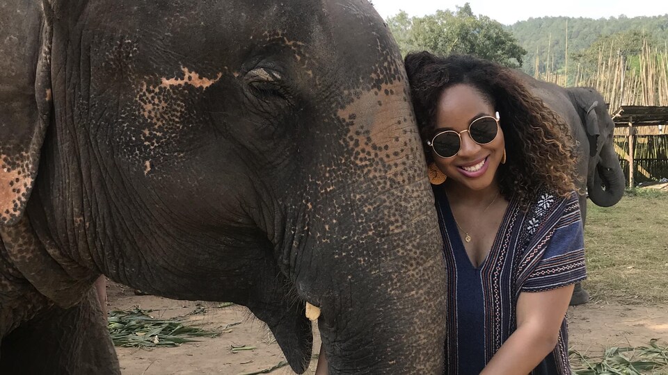 Une femme tient la trompe d'un éléphant.