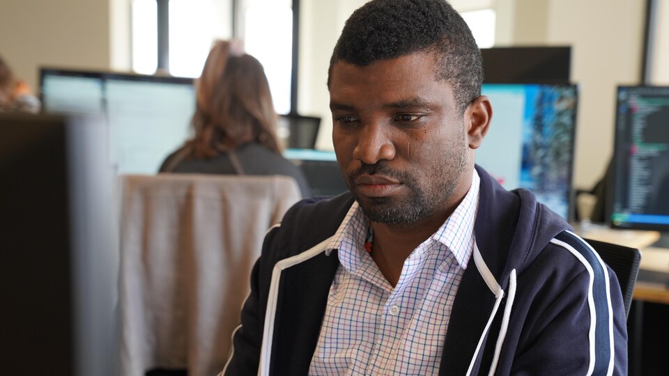 Daniel Afekhume, assis à son bureau en train de travailler devant un ordinateur.