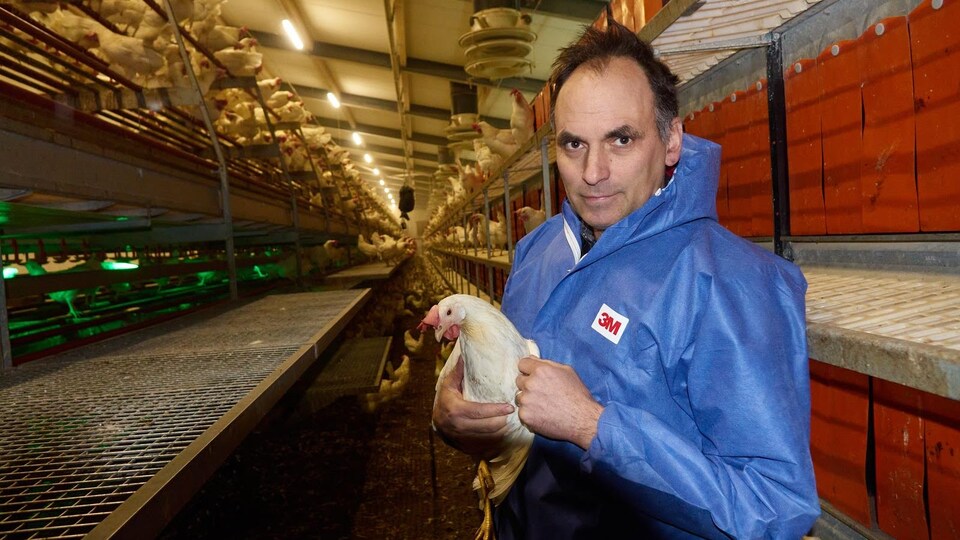 Daniel tient une de ses poules entre ses mains