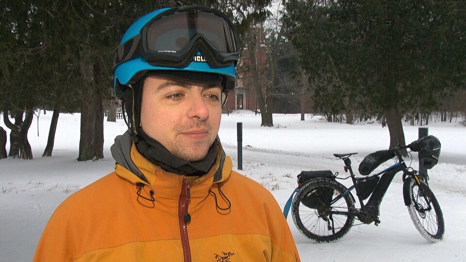 M. Varin est habillé chaudement à côté de son vélo d'hiver.