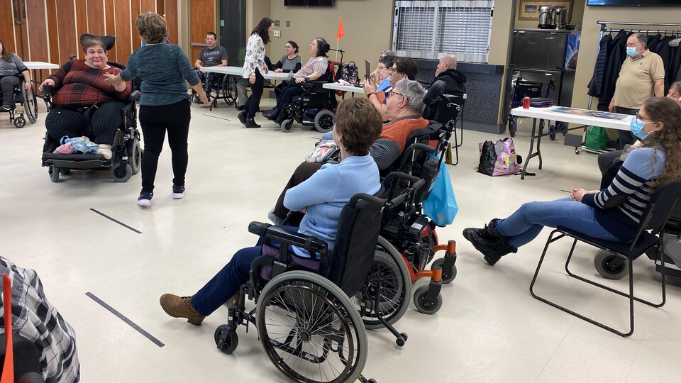 Une femme en fauteuil roulant danse devant un groupe avec une professeure.