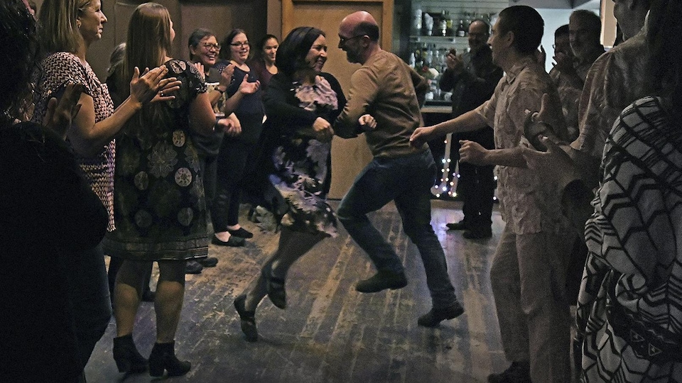 Un homme et une femme au milieu d'un groupe qui font des danses traditionnelles dans une taverne.