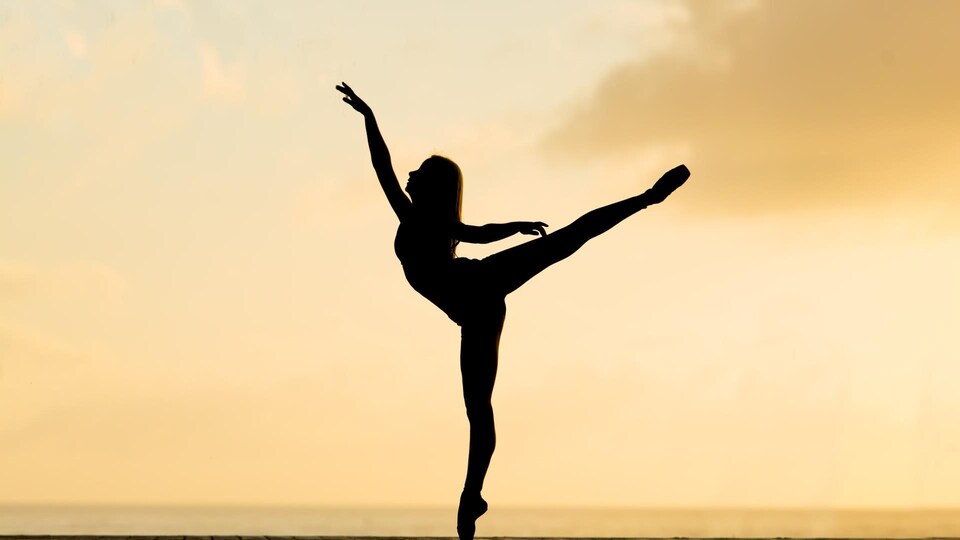 Une femme fait une arabesque.