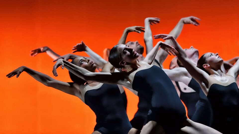 Des danseuses élèvent leurs bras dans les airs et se penchent vers leur droite en regardant le ciel.