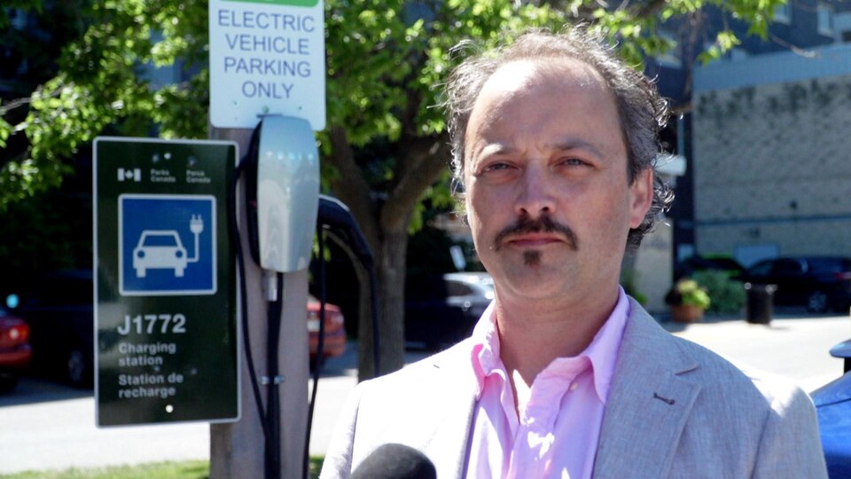Dany Robidoux, à côté d'uune borne de recharge pour voiture électrique à Winnipeg, le 9 août 2022.