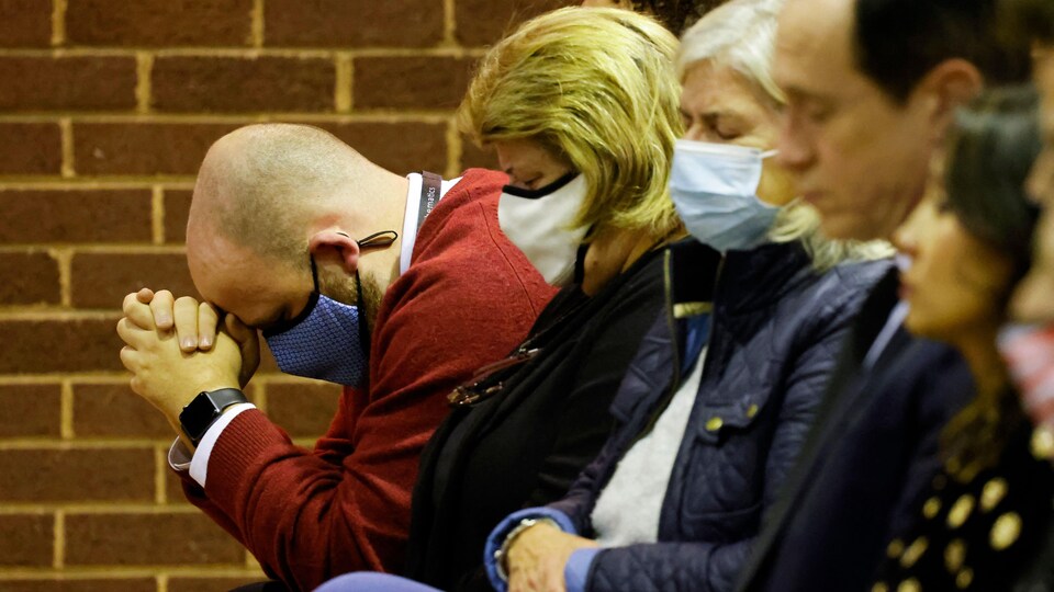 Une photo prise de côté de gens en plein recueillement à une messe.