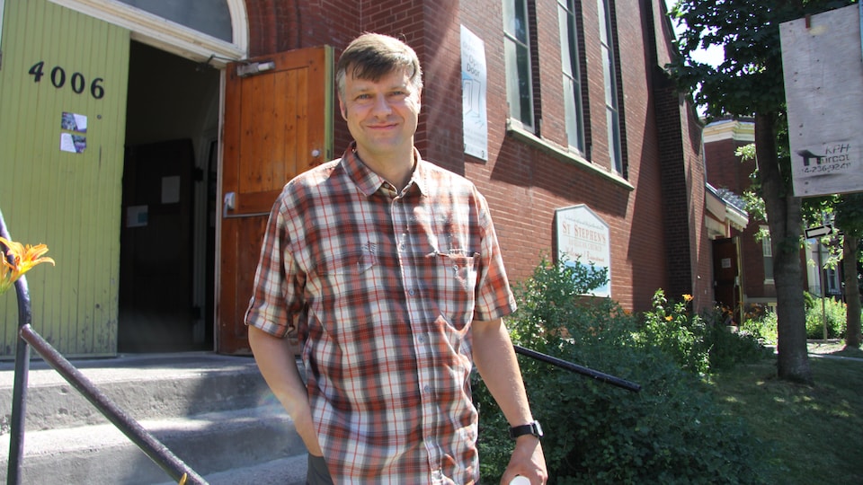 Un homme avec une chemise à carreaux pose devant l'église Saint-Stephen sur la rue Dorchester, à Montréal.