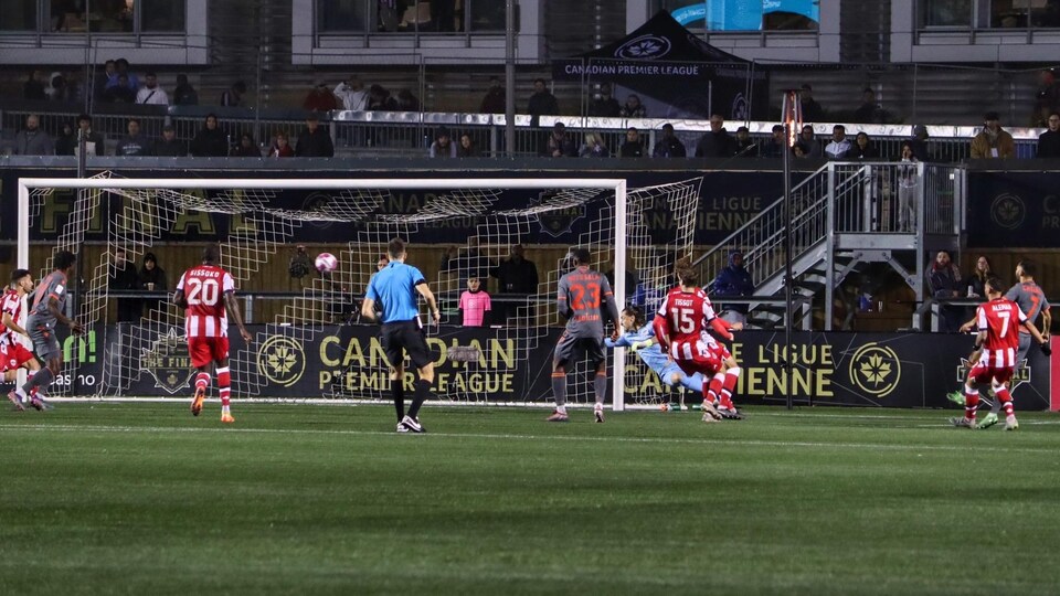 Les joueurs de deux équipes de soccer regarde le ballon entrer dans le but d'Ottawa.