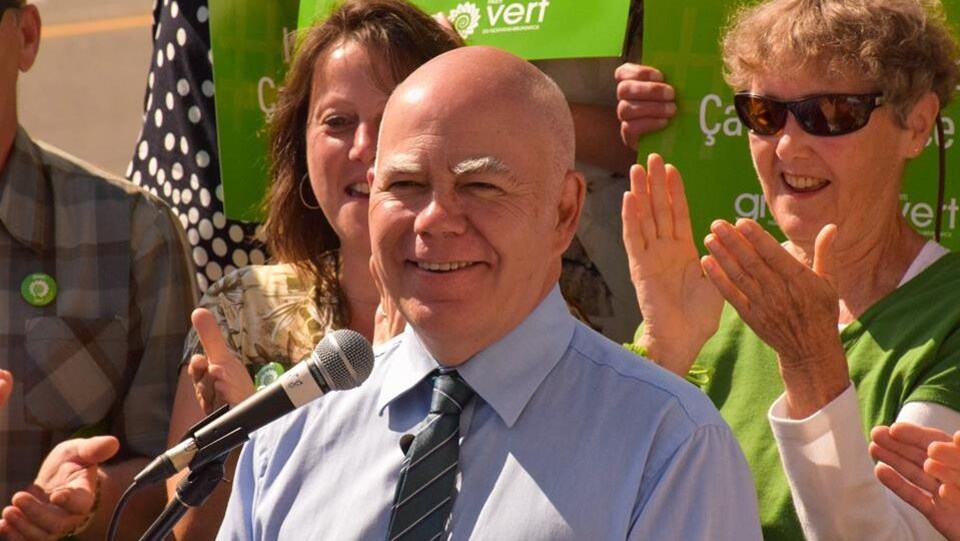 David Coon au micro lors d'un rassemblement de campagne. Des membres de son équipe l'applaudissent en arrière-plan.