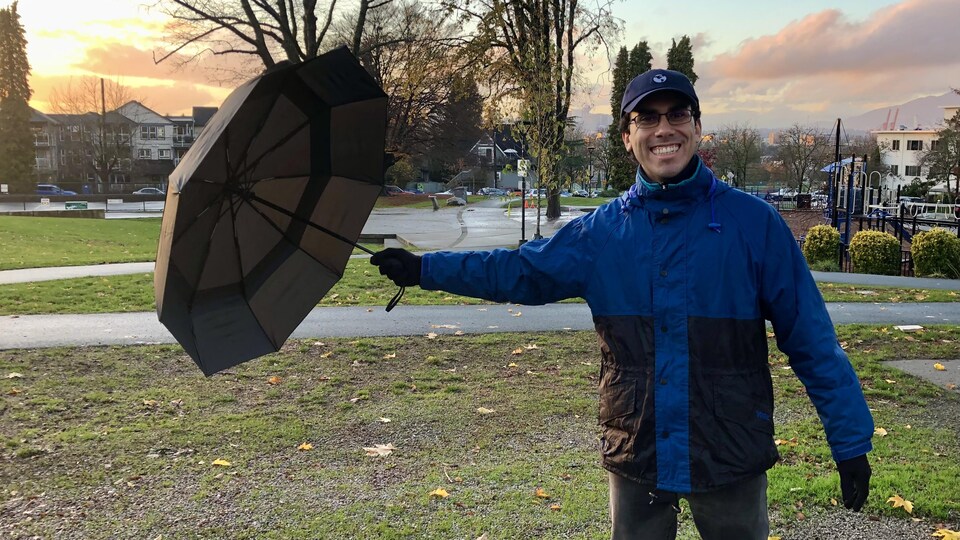 David Espinosa s'amuse avec son parapluie dans un parc au coucher du soleil.