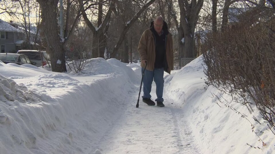 David Kron marche sur un trottoir enneigé de Winnipeg en janvier 2023. 