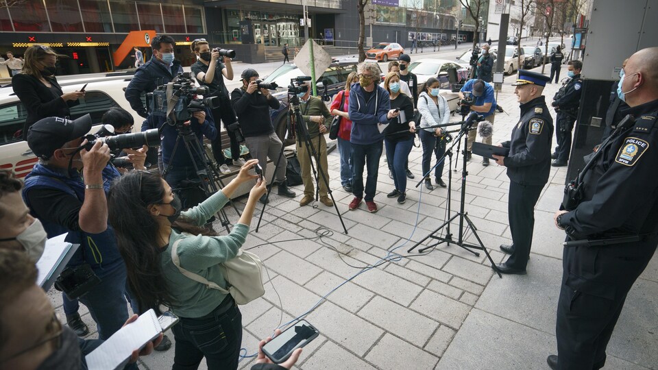 Un policier parle devant des journalistes et des photographes.