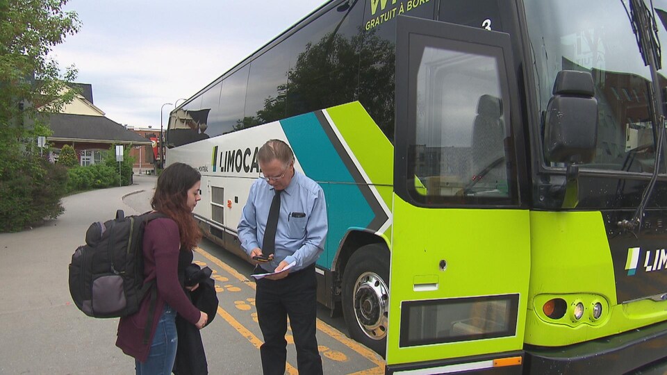 Une dame s'apprête à prendre place à bord d'un autobus Limocar à Sherbrooke. Le chauffeur valide son billet.