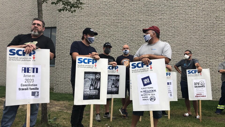 Des grévistes du SCFP tenant des pancartes appelant au respect de la conciliation travail-famille.