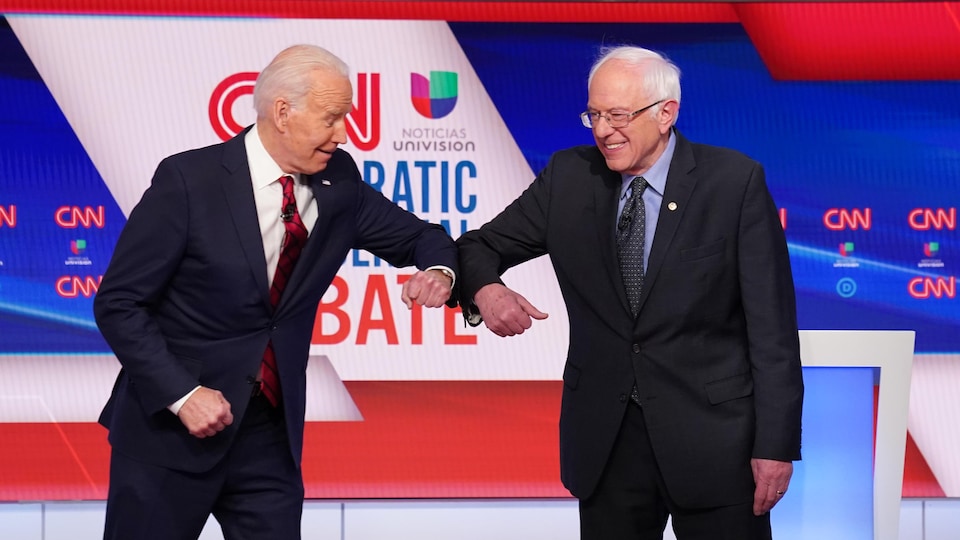 Joe Biden et Bernie Sanders se donnant un coup de coude.