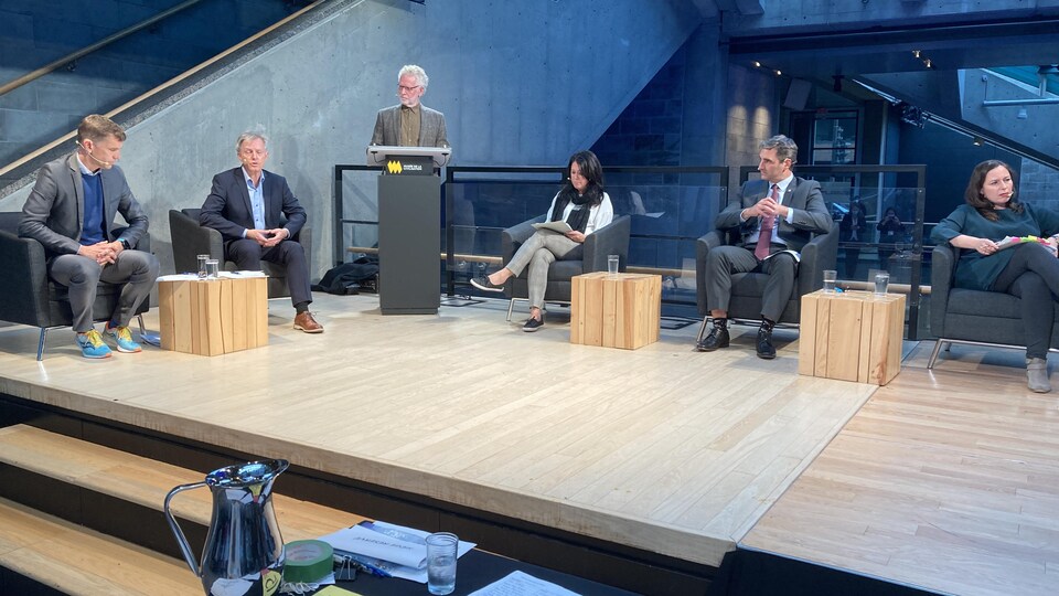 Les candidats sont assis chacun à un siège et participent à un débat.